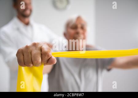 Paziente con terapia fisica che utilizza bande di fisioterapia per la riabilitazione Foto Stock