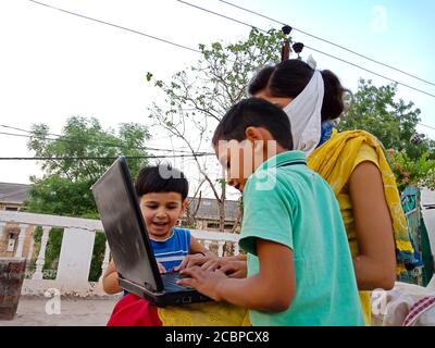 DISTRETTO KATNI, INDIA - 23 MAGGIO 2020: Un ragazzo indiano che impara la tecnologia dei laptop con la sorella maggiore in un ambiente aperto insieme. Foto Stock