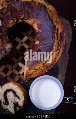 Colpo verticale di una deliziosa torta di libbre di marmo fatta in casa e. tazza di latte fresco su una tavola di ardesia Foto Stock