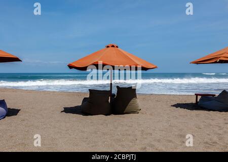 Ombrelli da sole arancioni e sacchi di fagioli vuoti sulla spiaggia di Berawa (Pantai Berawa), Canggu, Badung, Bali, Indonesia Foto Stock