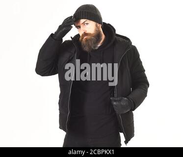 Macho con barba e baffi indossa giacca invernale, guanti e cappello. Concetto di abbigliamento invernale. Ragazzo in abito nero e brutale. L'uomo dal volto stretto indossa abiti caldi, isolati su sfondo bianco. Foto Stock