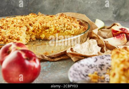 Torte fatte in casa, torta in una teglia con pesche e pere su cemento grigio-blu. Foto Stock