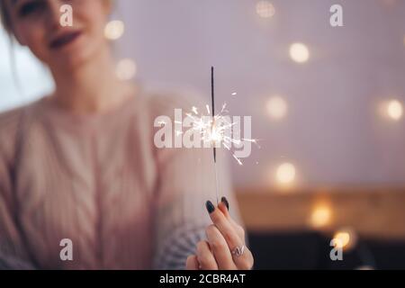 Giovane ragazza che tiene uno scintillatore in mani molto felice circa l'arrivo di Natale. Fuoco selezionato Foto Stock