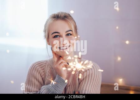 Giovane ragazza che tiene uno scintillatore in mani molto felice circa l'arrivo di Natale. Fuoco selezionato Foto Stock