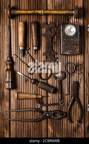 Collezione di strumenti arrugginiti e chiavi in stile vintage sfondo di legno Foto Stock