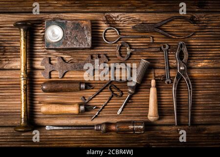 Collezione di strumenti arrugginiti e chiavi in stile vintage sfondo di legno Foto Stock