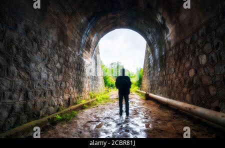 Silhouette viaggiatore uomo esplorato nel tunnel ferroviario antico, abbandonato 19 ° secolo architettura ad oggi vicino a da Lat, Vietnam Foto Stock