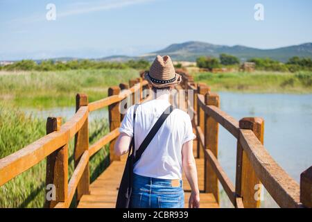 Giovane turista donna con cappello a piedi su sentiero in legno nel parco naturale Vrana lago (Vransko jezero), Dalmazia, Croazia, bella destinazione turistica Foto Stock