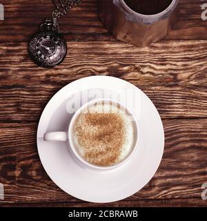 Tazza di caffè, orologio e caffettiera su sfondo di legno Foto Stock