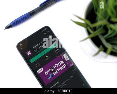 LOD, Israele - 8 luglio 2020: Moderno spazio di lavoro minimalista per ufficio con smartphone nero mobile con l'app Cellcom play pagina del negozio su sfondo bianco. Cl Foto Stock