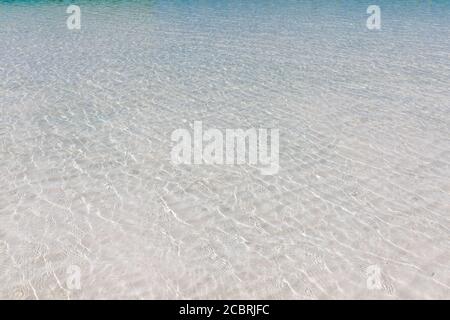 Acqua increspata, acqua increspata trasparente, onde di sabbia e luce solare bagliore. Fondo del pavimento del mare Foto Stock