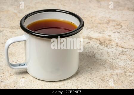 tazza di tè caldo in smalto metallico su piastrelle in ceramica sfondo Foto Stock