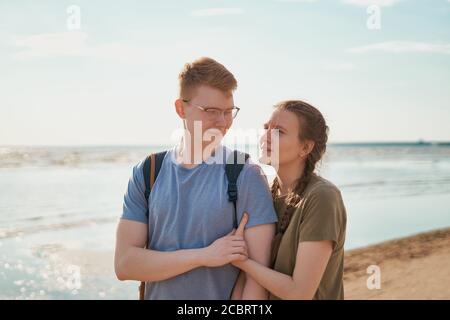Millennial coppia abbracciando e posando sulla spiaggia in giornata di sole Foto Stock