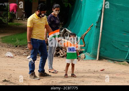 Una ragazza adorabile vestita come tricolore e ha scritto L'INDIA su di esso, tenendo bandiera nazionale tricolore, indossando maschera di stoffa che celebra la giornata di indipendenza indiana nella capitale nazionale Delhi in mezzo al Covid-19 pandemia di coronavirus focolaio nell'anno di 2020 Foto Stock