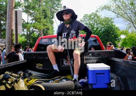Stone Mountain, Georgia, Stati Uniti. 15 agosto 2020. Un uomo armato di fucile si siede sul retro di un camion durante un raduno di "Defend Stone Mountain". Sabato sono stati arenati numerosi gruppi di milizie di destra e contro manifestanti per convergere a Stone Mountain, Georgia. Credit: Young G. Kim/Alamy Live News Foto Stock