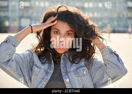 Cool gen z afro American teen girl pouting labbra sulla soleggiata strada della città, ritratto. Foto Stock