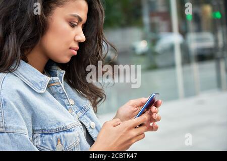 Giovane ragazza africana teen in piedi sulla strada della città con smartphone utilizzando le app. Foto Stock