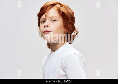 Adolescente rosso in t-shirt bianca vista tagliata di sfondo grigio Foto Stock