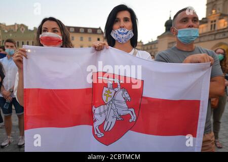 Cracovia, Polonia. 15 agosto 2020. Durante la manifestazione un protestore detiene una bandiera bielorussiana bianca-rossa-bianca di opposizione. Centinaia di persone bielorusse che vivono a Cracovia e sostenitori locali si sono riuniti durante il Rally di solidarietà organizzato nella Piazza del mercato di Cracovia, fuori dal monumento Adam Mickiewicz contro il leader bielorusso, Alexander Lukashenko. Credit: SOPA Images Limited/Alamy Live News Foto Stock