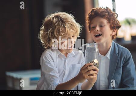 Due ragazzi guardando il vaso con le monete e guardando interessato Foto Stock