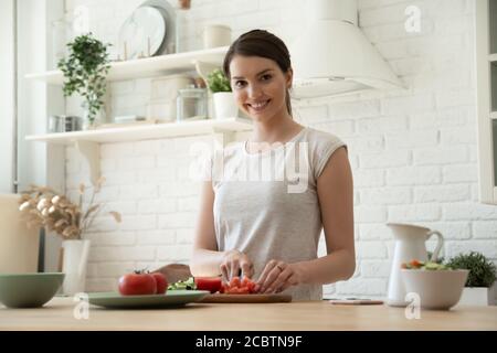 Ritratto di felice millennial femmina che prepara insalata di verdure a casa Foto Stock