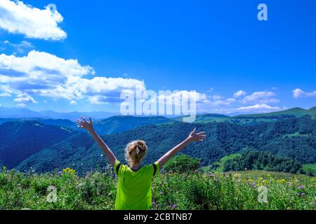 giovane turista che alza le mani e gode di una vista fantastica sulla natura, la foresta e le montagne alpine. Paesaggio montuoso Foto Stock