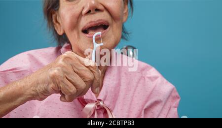 Caregiver prendere cura donna anziana asiatica mentre si usa il bastone fross dentale. Foto Stock