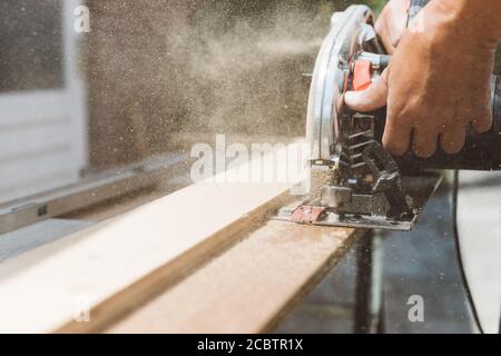 Falegname usando sega circolare di potere per tagliare legno, miglioramento domestico, fallo voi stessi (DIY) e concetto di lavori di costruzione, colpo d'azione Foto Stock