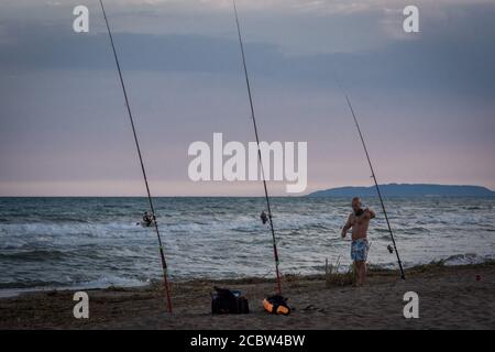 Il pescatore prepara le canne da pesca sulla spiaggia di Delta de l'Ebre Eucaliptus a Tarragona, Catalogna, Spagna Foto Stock