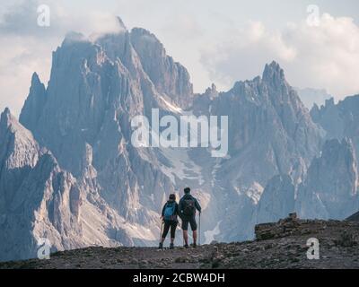 Coppia di escursionisti che si levano in piedi e ammirano la bellezza stupefacente delle cime frastagliate impressionanti del gruppo dei Cadini di misurina nelle Dolomiti, Italia, parte del Tr Foto Stock