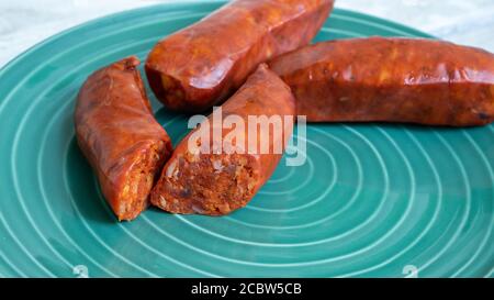 Salsiccia piccante chorizo tagliata aperta e in mostra su un piatto verde. Può essere usato come una foto di concetto di cibo piccante. Foto Stock