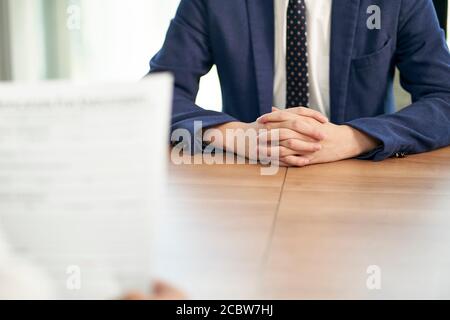 job seeker asiatico intervistato dal responsabile delle risorse umane in carica, concentrarsi sulle mani del candidato Foto Stock