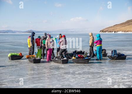 Un gruppo di turisti con slitte di ghiaccio sulla superficie congelata del Lago Baikal, Russia Foto Stock