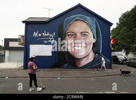 Megan Nicell, sorella di Suor Clare Crockett, e Danny Doyle, padrino e zio della suora tarda, riordinano la strada di fronte ad un nuovo murale di Suor Crockett davanti ad un servizio di benedizione per il murale di Domenica sera. Il murale di Suor Crockett, che fu ucciso in un terremoto in Ecuador nel 2016, fu dipinto dalla compagnia UV Arts vicino alla sua casa a Brandywell, Derry. Foto Stock