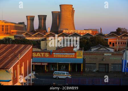 Il sole sorge illuminando la centrale elettrica di Bulawayo e l'adiacente quartiere. Foto Stock