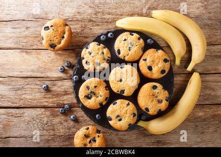 Muffin dietetici fatti in casa con mirtilli e banane da vicino su una tavola di ardesia sul tavolo. Vista dall'alto orizzontale Foto Stock