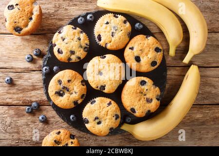 Muffin appena sfornati con mirtilli e banane da vicino su una tavola di ardesia sul tavolo. Vista dall'alto orizzontale Foto Stock