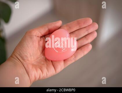 una donna tiene in mano un sapone a forma di cuore. Cuore simbolo dell'amore - vi innamorate della luna e della schiena Foto Stock