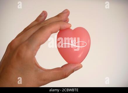 una donna tiene in mano un sapone a forma di cuore. Cuore simbolo di amore. Cuore rosa Foto Stock