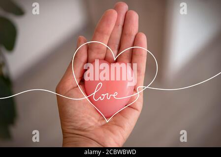 una donna tiene in mano un sapone a forma di cuore. Cuore simbolo di amore. Cuore rosa Foto Stock