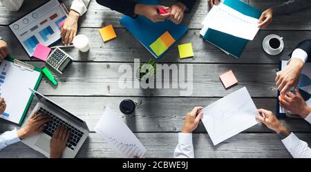 Concetto di team di pianificazione aziendale, persone sedute intorno al tavolo dell'ufficio e che lavorano con i report dei dati finanziari Foto Stock