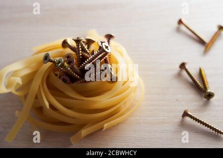 Le viti giacciono nel nido di spaghetti di fondo leggero Foto Stock