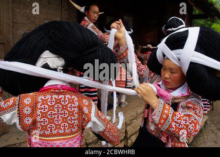 Cina. Provincia di Guizhou. Longjia villaggio. Long Horn Miao ragazze in costumi tradizionali che celebrano Flower Dance Festival. Foto Stock