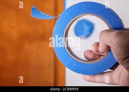 Mano con nastro di mascheratura blu da vicino Foto Stock