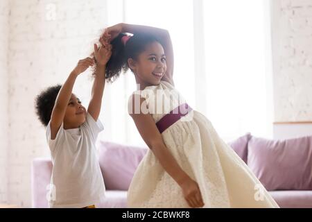 Sorella maggiore nera che balla in soggiorno con il fratello minore Foto Stock