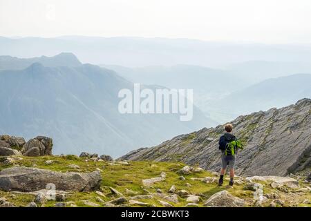 Ragazzo adolescente a Three Tarns a Bowfell, Lake District National Park. Langdale Pikes in lontananza Foto Stock