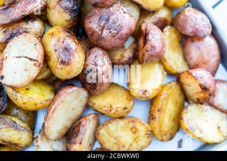 Grigliare piccole patate con fettine di aglio su una piscina grill a gas. Foto Stock