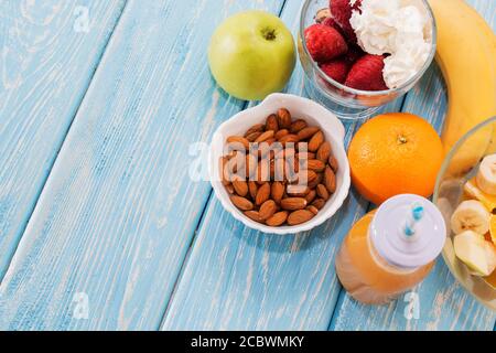 Colazione tradizionale americana ed europea estiva: frutti di bosco, mela alla frutta, fragola, arancia, banana. Tabella blu chiaro. Spazio per la copia. Foto Stock