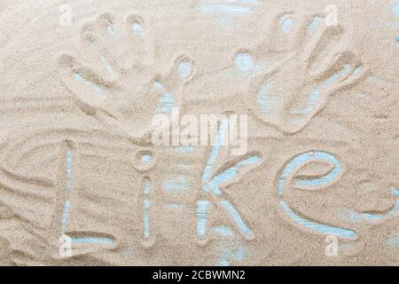 Parola scritta a mano COME sulla sabbia marrone sulla spiaggia in giornata di sole. Foto Stock