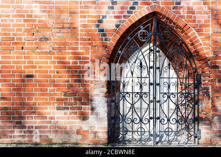 Una vecchia porta di ferro in un vecchio muro di mattoni, fortificazione. Foto Stock